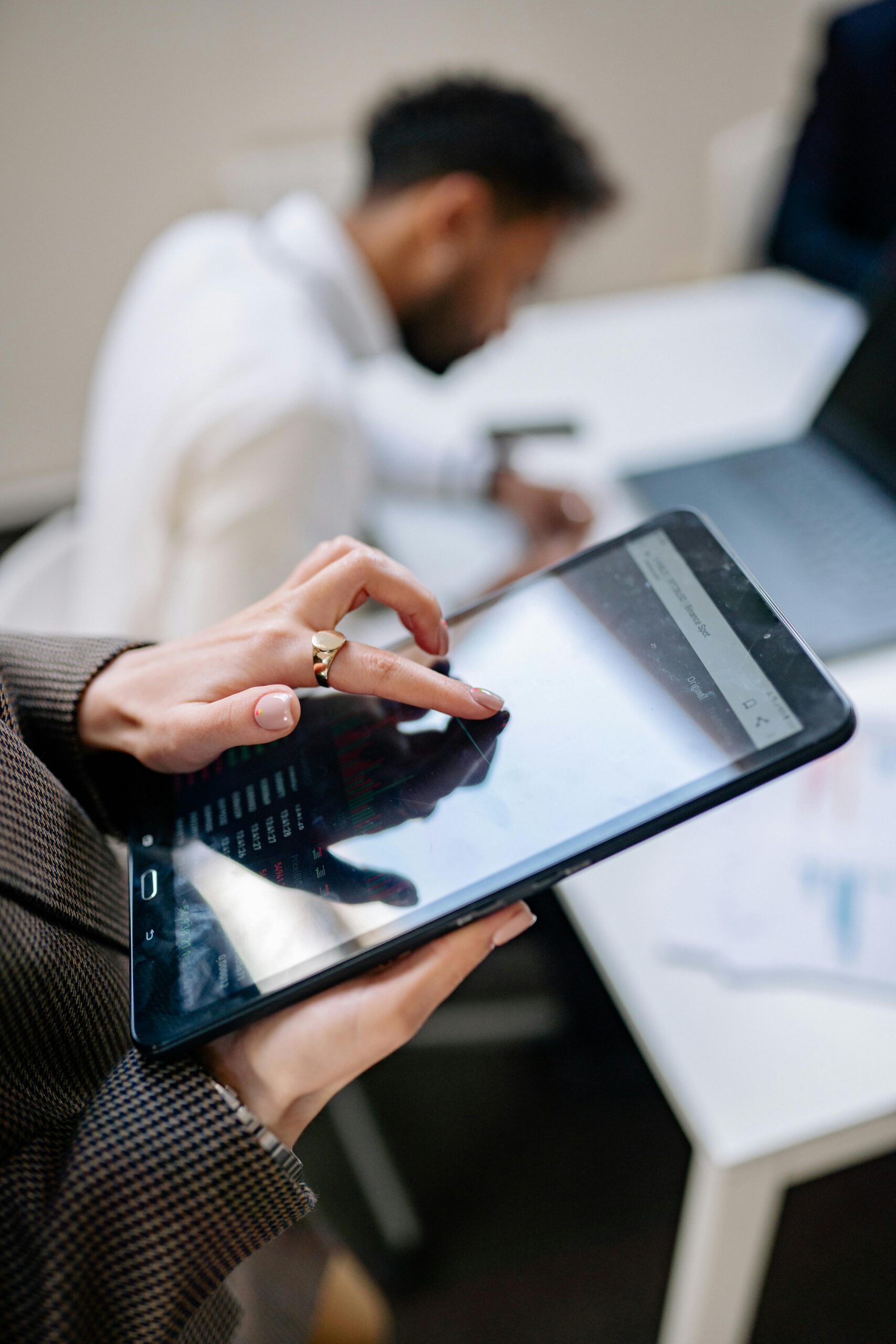 Close-up of a person using a tablet in an office setting, focusing on technology at work.
